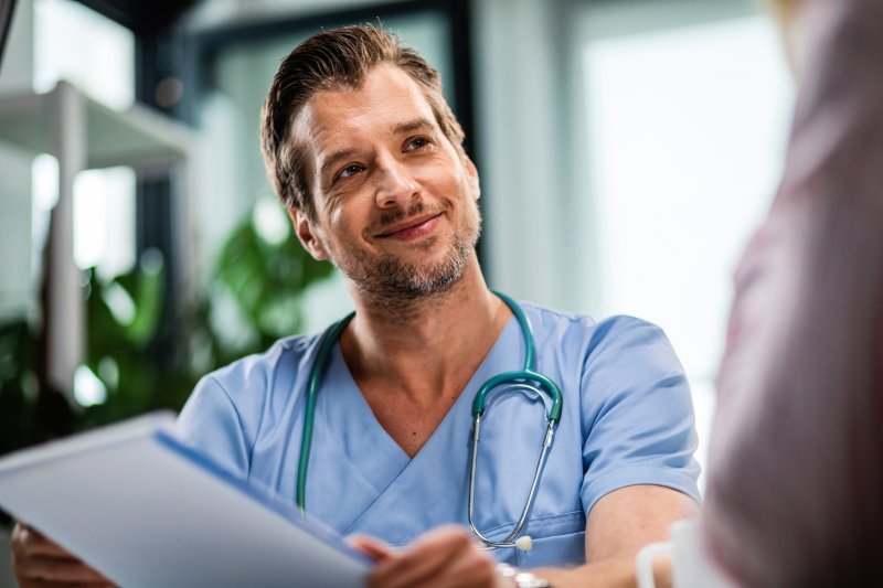 Médecin souriant en tenue bleue avec un stéthoscope, offrant une consultation chaleureuse et professionnelle, représentant des soins médicaux de haute qualité avec ROYAL MEDICAL.
