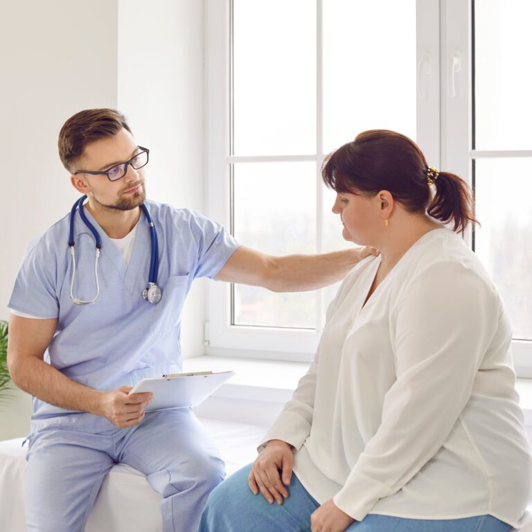 Doctor in blue scrubs consulting with a female patient about lipedema, providing compassionate care and expert advice for medical travel solutions with ROYAL MEDICAL.
