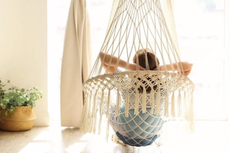 Woman relaxing in a macrame hammock chair in a bright interior, calm and mindful atmosphere