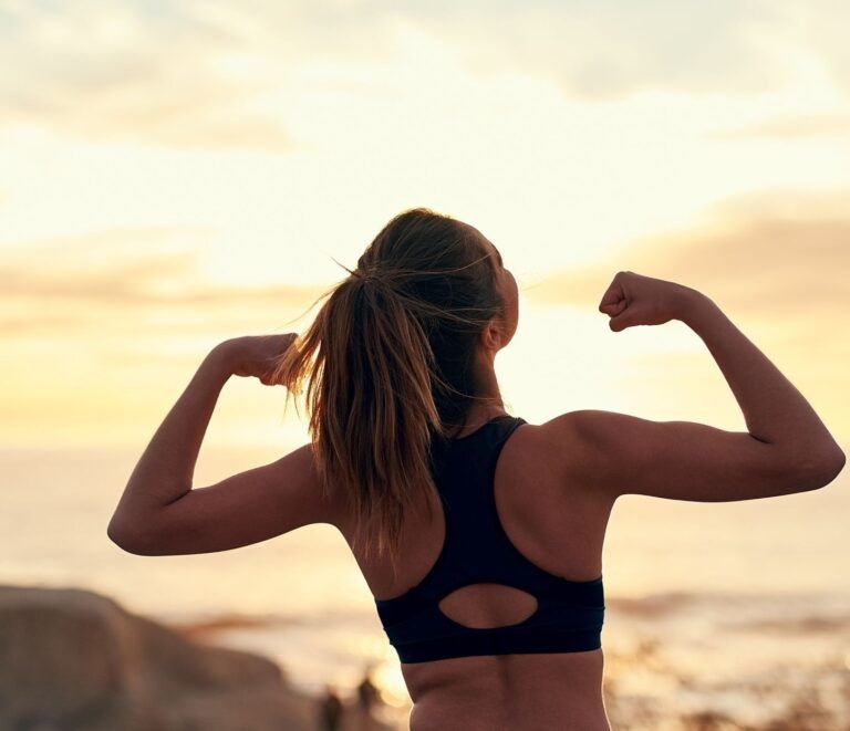 Woman showing strength and confidence at sunset, symbolizing inner health and radiant skin supported by omega-3 fatty acids.